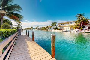 a wooden dock in a body of water with houses at Canal-side Charisma in Key Colony Beach