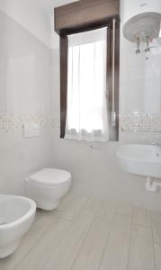 La salle de bains blanche est pourvue de 2 lavabos et de toilettes. dans l'établissement Condominio Pleione, à Bibione