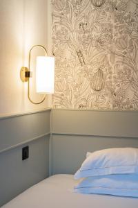 una camera da letto con un letto con una lampada e carta da parati di Hôtel De Fleurie a Parigi