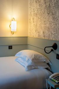 um quarto com uma cama com um candeeiro e uma mesa em Hôtel De Fleurie em Paris