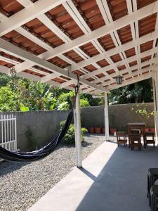 a patio with a hammock under a wooden pergola at Casa Completa 2 Quartos in Penha