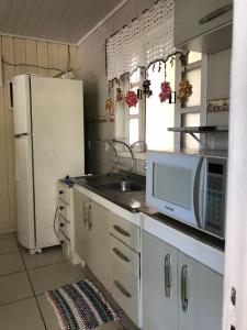 a kitchen with a white refrigerator and a microwave at Casa Completa 2 Quartos in Penha