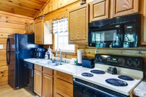 eine Küche mit einem Herd, einer Spüle und einem Kühlschrank in der Unterkunft Tennessee Cabin with Balcony, Hot Tub and Pool Access! in Sevierville