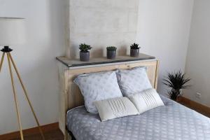 a bed with two pillows and potted plants on a shelf at La Patte Charentaise Parking gratuit Le calme en ville in Saintes