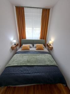 een slaapkamer met een bed met 2 kussens en een raam bij LUX APARTMAN PANORAMA in Bečej