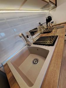 a kitchen sink with a dish drying rack above it at LUX APARTMAN PANORAMA in Bečej
