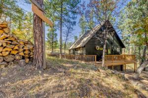 a cabin in the woods with a pile of wood at Ruidoso Rental with Private Hot Tub Walk to Midtown in Ruidoso