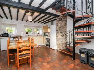 a kitchen with a wooden table and a spiral staircase at The Barn in Mold