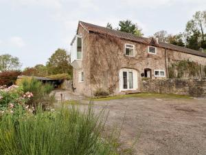 an old stone house with a yard in front of it at The Barn in Mold