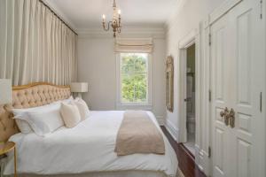 um quarto branco com uma cama grande e uma janela em Leland Suite at Mirabelle em Savannah