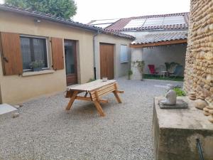 a patio with a wooden picnic table in front of a house at SCI la malinoise in Albon