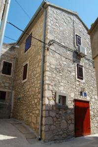 un antiguo edificio de piedra con una puerta roja en Beach House Tribunj en Tribunj