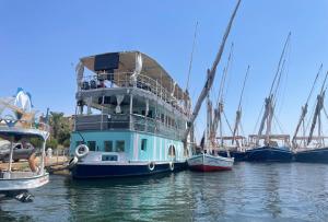 un barco está atracado en el agua con otros barcos en Floating Hotel- Happy Nile Boat, en Luxor