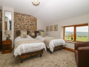 een slaapkamer met 2 bedden en een stenen muur bij Cuthbert Hill Farm in Preston