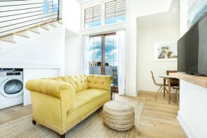 a living room with a yellow couch and a tv at 2BR Loft with Terrace in Savannah