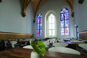 um quarto com mesas e cadeiras e vitrais em HOPPER Hotel St. Josef em Colónia