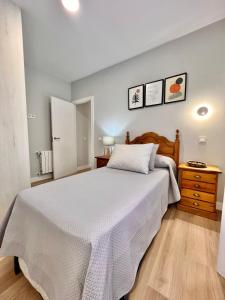 una camera con un grande letto bianco e un comò in legno di Apartamento reformado centro de Santander a Santander