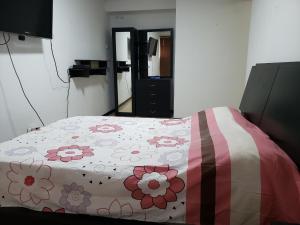 Un dormitorio con una colcha con flores. en Apartamento los caobos, en Caracas