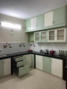a kitchen with green and white cabinets and counters at Bigson Service Apartments, Kondapur in Hyderabad