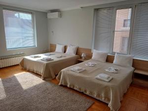 two beds sitting next to each other in a room with windows at Guest Rooms DEVA in Burgas City