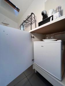 a kitchen with a white refrigerator and a shelf at Studio proche Stade de France in Saint-Denis