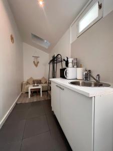 a white kitchen with a sink and a microwave at Studio proche Stade de France in Saint-Denis