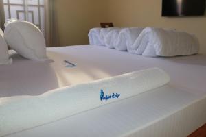 a white bed with a rolled up towel on it at Verified Lodge in Dodoma