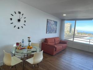 a living room with a table and a couch and a clock at Apartamento en primera línea de playa in Puerto de la Cruz
