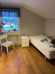 ein Schlafzimmer mit einem Bett, einem Stuhl und einem Fenster in der Unterkunft Lantligt boende in Luleå