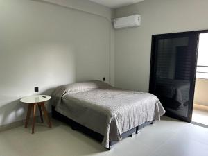 a bedroom with a bed and a small table at Studios Mobiliados - Ambar Ipanema in Sinop