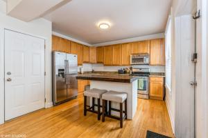 a kitchen with wooden cabinets and stainless steel appliances at Belmont & Racine - Walk to Wrigley & Southport Corridor & Belmont L Train Station! in Chicago