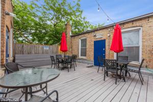 a deck with tables and chairs and red umbrellas at Belmont & Racine - Walk to Wrigley & Southport Corridor & Belmont L Train Station! in Chicago