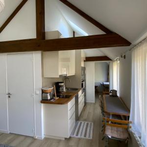 una cucina con armadi bianchi e soffitto in legno di La Maisonnette a Senlis