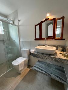 uma casa de banho com um lavatório, um WC e um espelho. em Casa Arte Cabore em Paraty