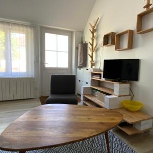 un soggiorno con tavolo in legno e TV di La Maisonnette a Senlis