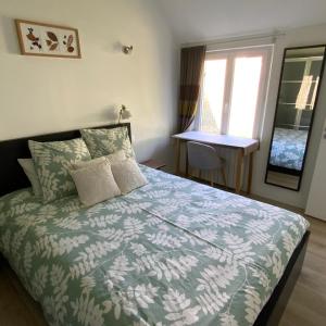 una camera da letto con un letto con un piumone verde e una finestra di La Maisonnette a Senlis