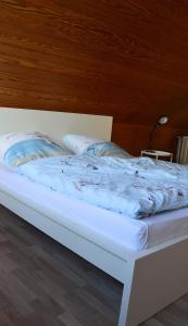 een wit bed met een blauw dekbed erop bij Ferienhaus Marlies und Piet in Bremerhaven