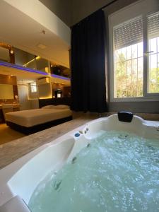 a large bath tub in a room with a bedroom at Drops Motel Porto Alegre in Porto Alegre