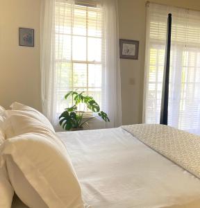 a bedroom with a white bed with white sheets and windows at Downtown Mobile, AL 2 Bedroom Townhome - Walk to Everything! in Mobile