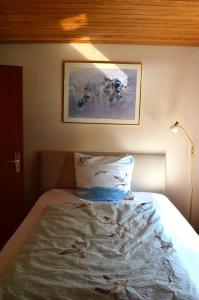 een bed met een kussen en een schilderij aan de muur bij Ferienhaus Marlies und Piet in Bremerhaven