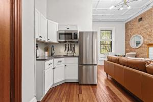 una cucina e un soggiorno con armadi bianchi e divano di Newly Renovated 2BR Haven Walk to Columbia Uni a New York