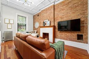 sala de estar con sofá de cuero marrón y pared de ladrillo en Newly Renovated 2BR Haven Walk to Columbia Uni, en Nueva York