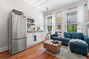 a living room with a blue couch and a kitchen at Newly Renovated 3BR Oasis Walk to Columbia Uni in New York