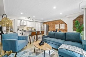 a living room with blue couches and a kitchen at Newly Renovated 2BR w Rare Private Backyard and BBQ in New York