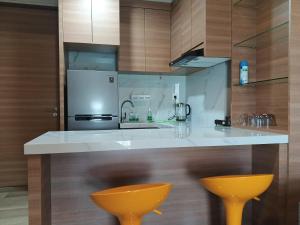 a kitchen with a white counter and two yellow stools at Peaceful Sea view Cozy APT at Batam Center - By MESA in Batam Center