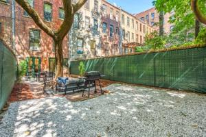 a patio with a tree and a bench and a fence at Newly Renovated 2BR w Rare Private Backyard and BBQ in New York