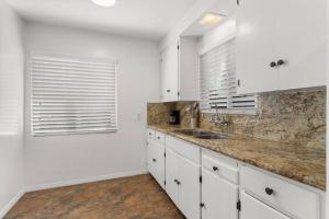 una cocina con armarios blancos y fregadero en Cozy, home with hottub and patio, en San Diego