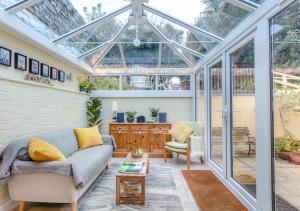 einen Wintergarten mit einem Sofa und einem Glasdach in der Unterkunft Drum Cottage in Appledore