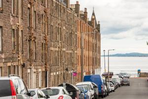 a row of cars parked on a street next to buildings at 425 Quirky and charming 2 bedroom seaside apartment in Portobello in Edinburgh