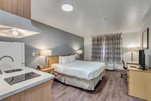 a hotel room with a bed and a sink at Suburban Studios Salt Lake City Airport in Salt Lake City